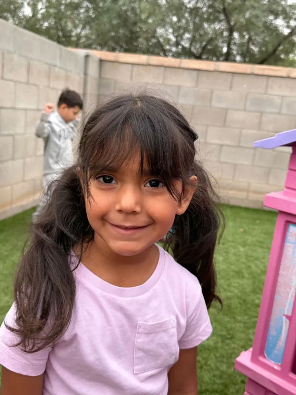 A smiling girl in the backyard at Angelita's Little Angels, Tucson