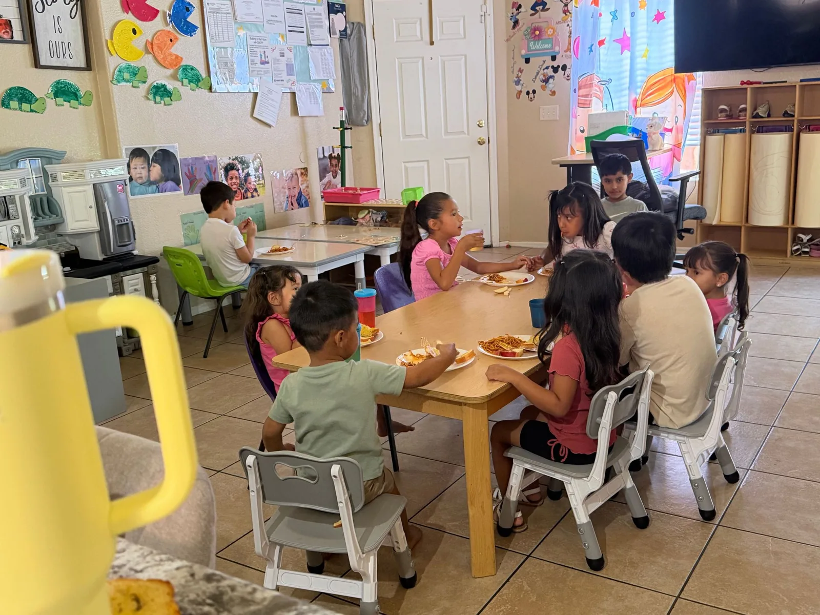 Children eating lunch together at the big table in the playroom